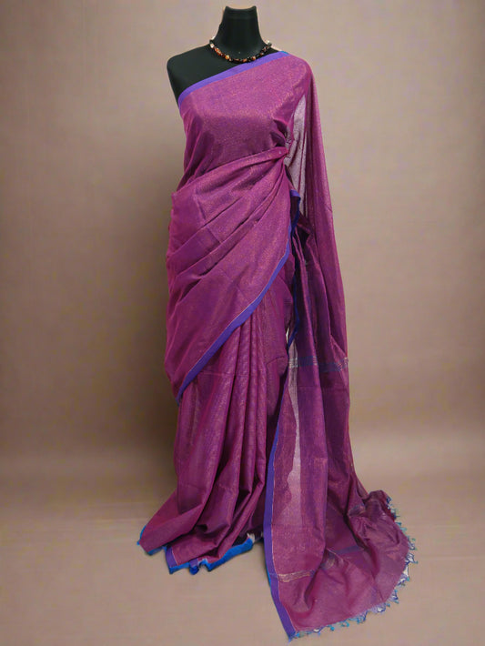 A purple and golden khadi cotton saree with golden zari stripes and tassels displayed on a mannequin alongside decorative items.