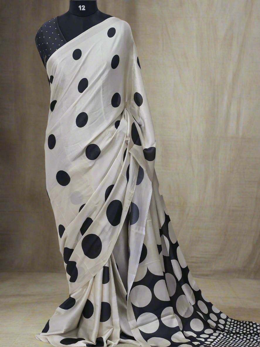 White saree with black polka dots on a mannequin against a white background, branded 'Aurat Designs'.