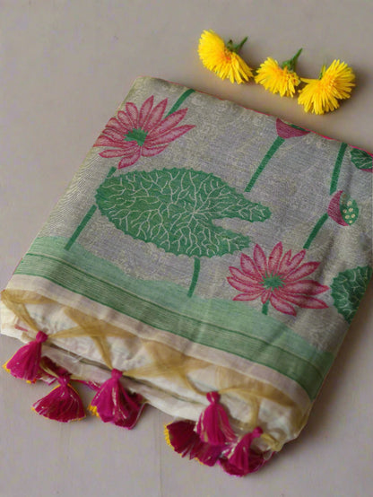 Muga cotton silk saree with thread woven pink lotus design, displayed on a white surface with a pink and green floral pattern, including a matching pink blouse piece.