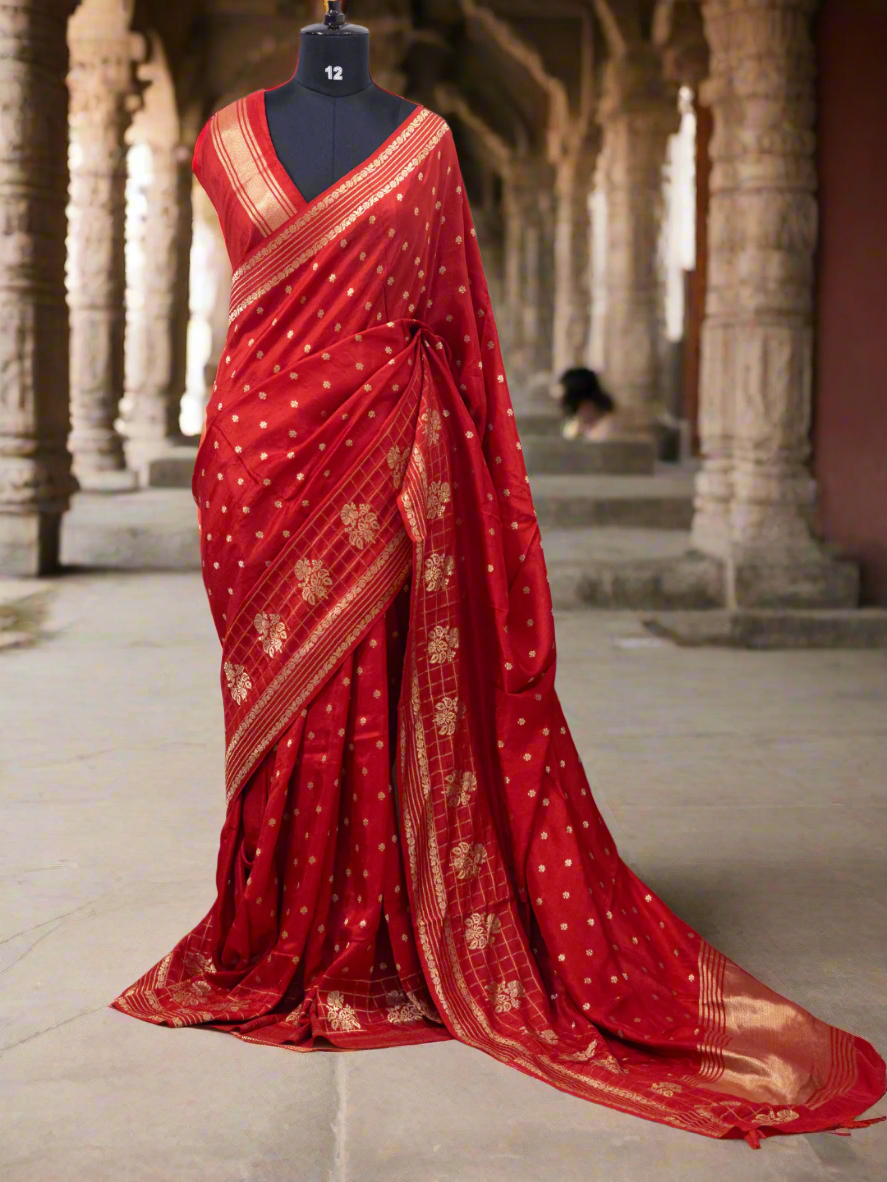 Red saree with gold patterns on a mannequin against a white curtain background, branded 'Aurat Designs'.