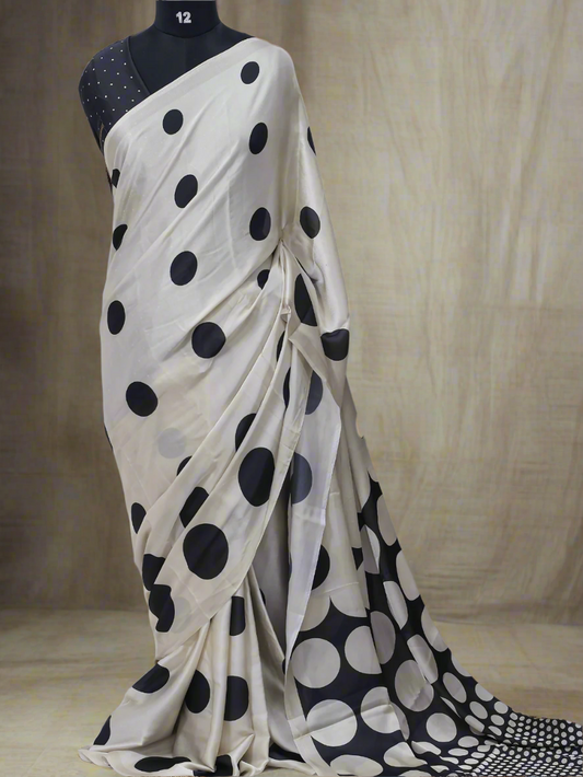 White saree with black polka dots on a mannequin against a white background, branded 'Aurat Designs'.